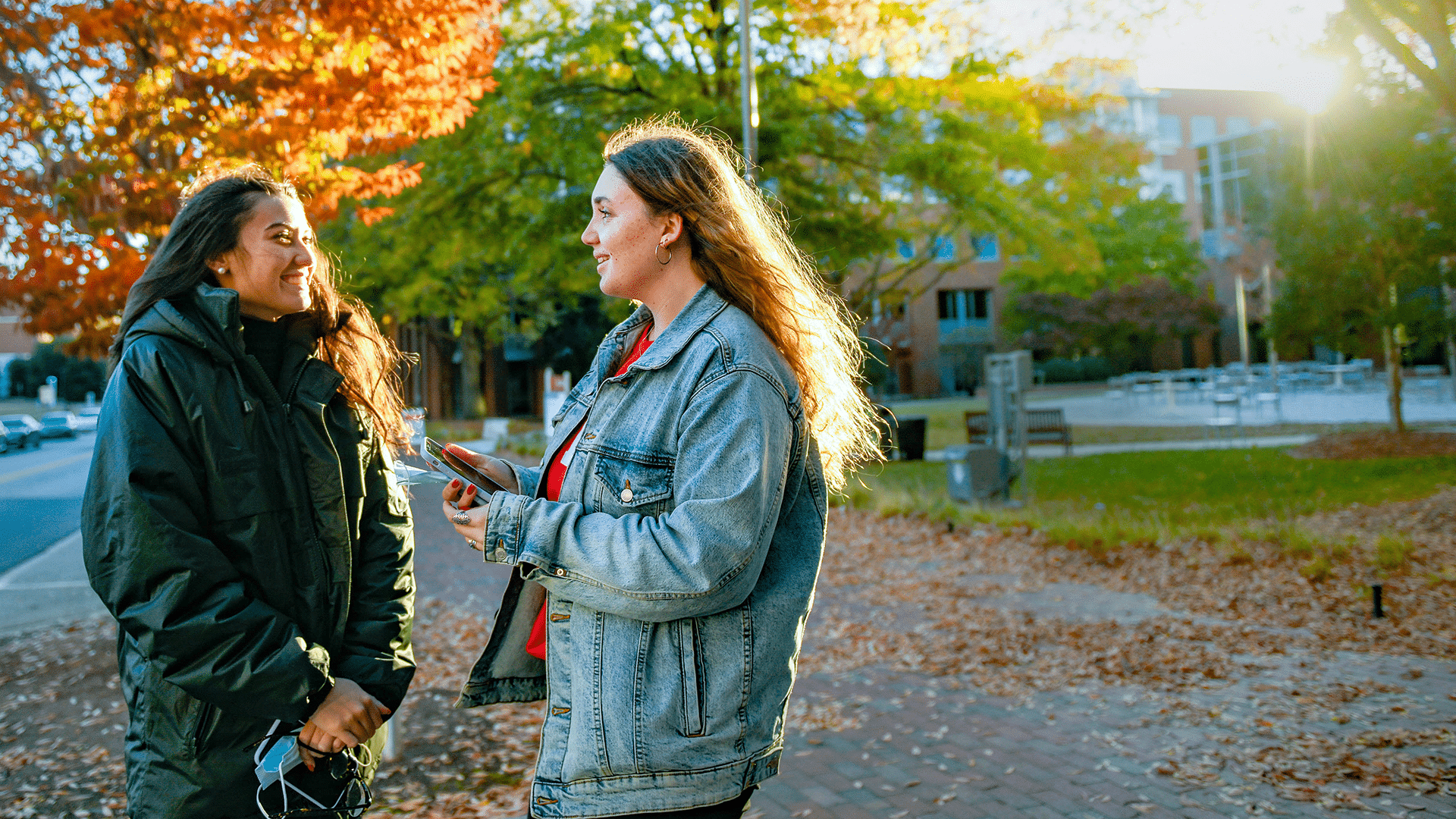 Two students talk on Centennial Campus on a sunny day.