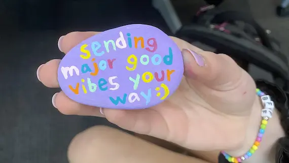 A painted rock created at a drop-in space on campus reads "Sending major good vibes your way."