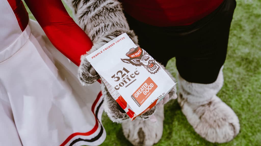 Mr. Wuf and Ms. Wuf hold a bag of Greater Good coffee