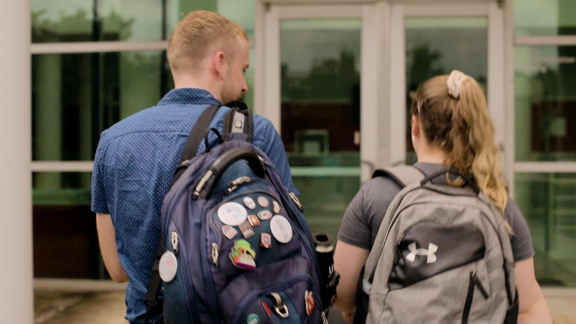 Two students walk into an academic building.