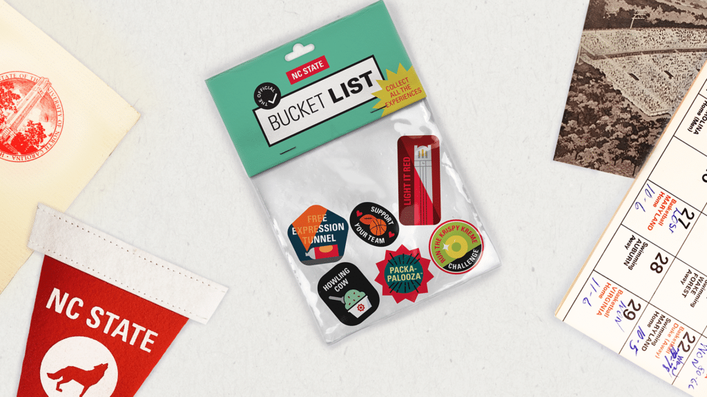 A plastic back labeled "The Official NC State Bucket List," filled with stickers that represent different bucket list items.