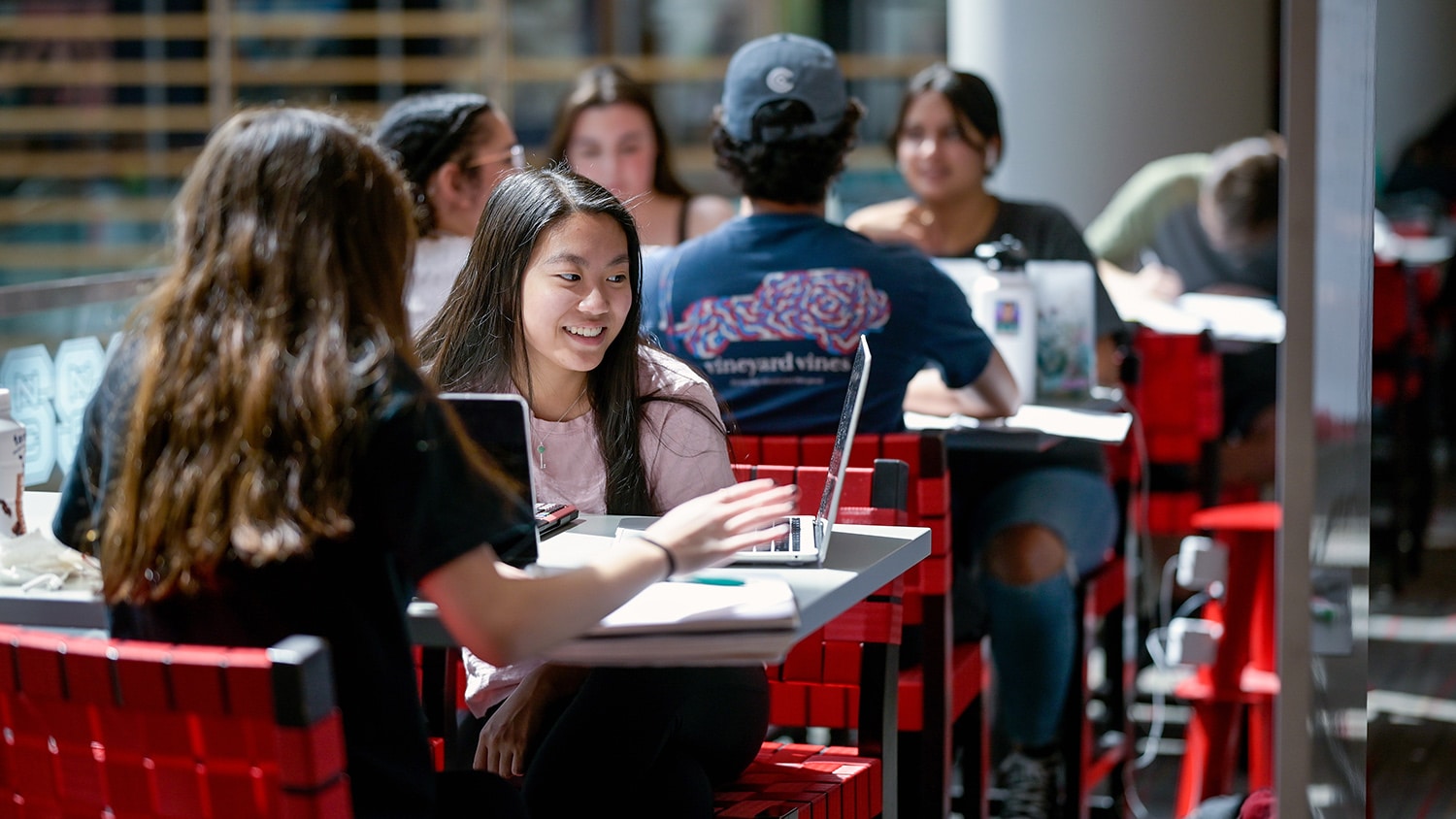 Two students sit together at a table in Talley, looking at something on a laptop screen.