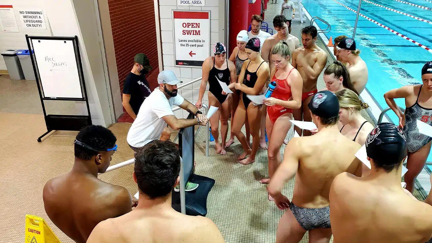 Wolfpack swimmers stand near the pool.