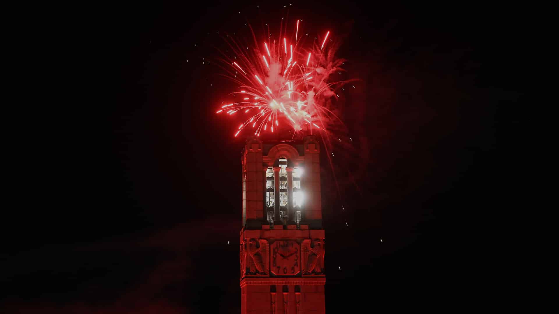 Red fireworks explode above the Memorial Belltower.