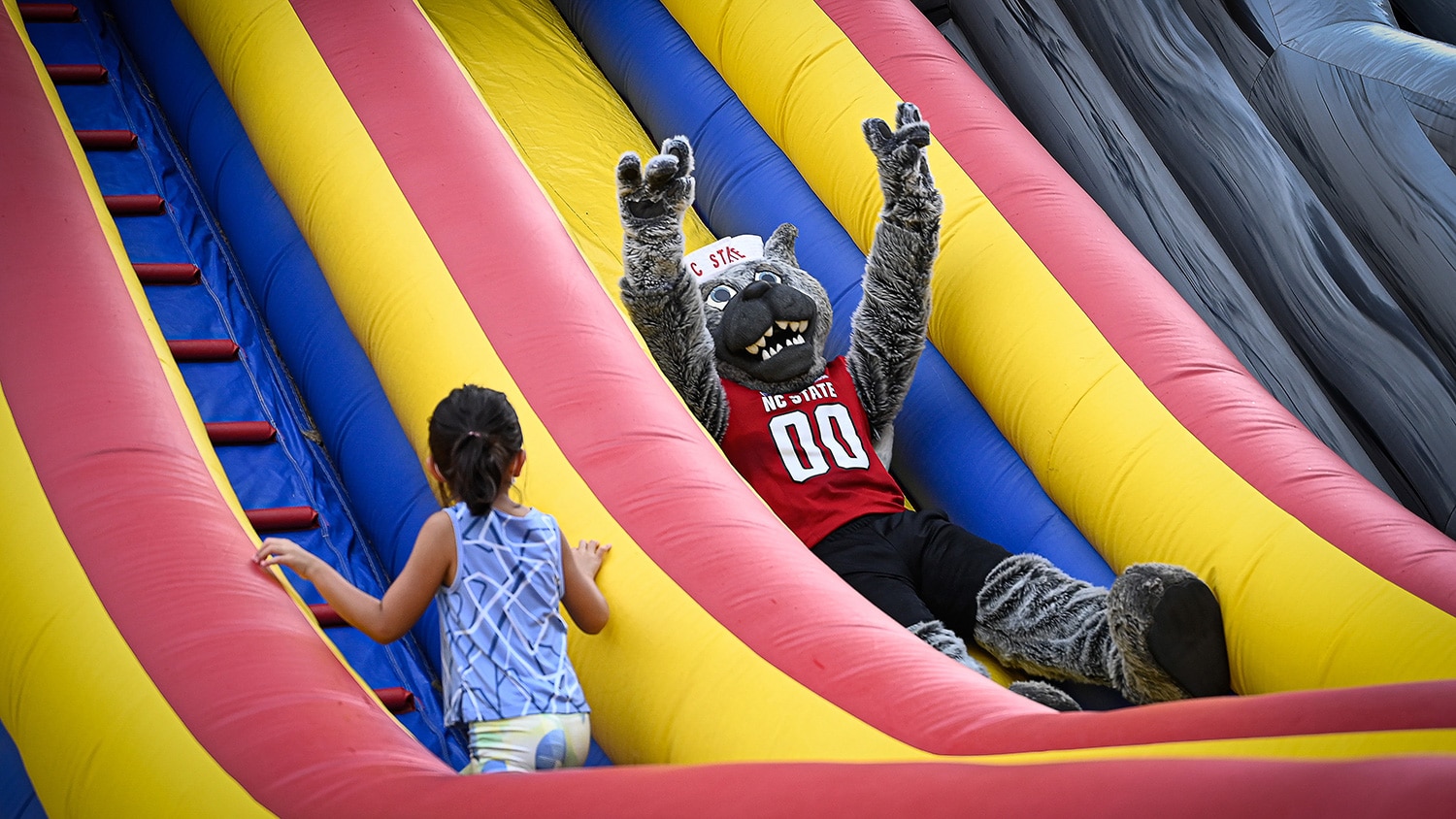 Mr. Wuf slides down an inflatable slide.