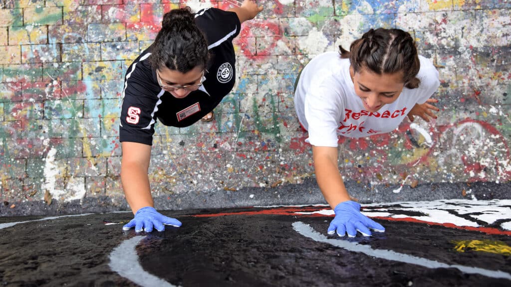 Two student leaders help paint the Free Expression Tunnel during the annual Respect The Pack event.