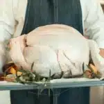 An uncooked turkey on a platter at Thanksgiving.