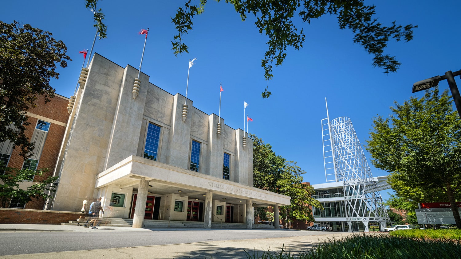 The exterior of Reynolds Coliseum and the Talley technology tower during the day.