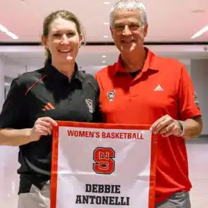 Athletic director Boo Corrigan presents Debbie Antonelli with a banner that will be displayed in the Ring of Honor at Reynolds Coliseum.