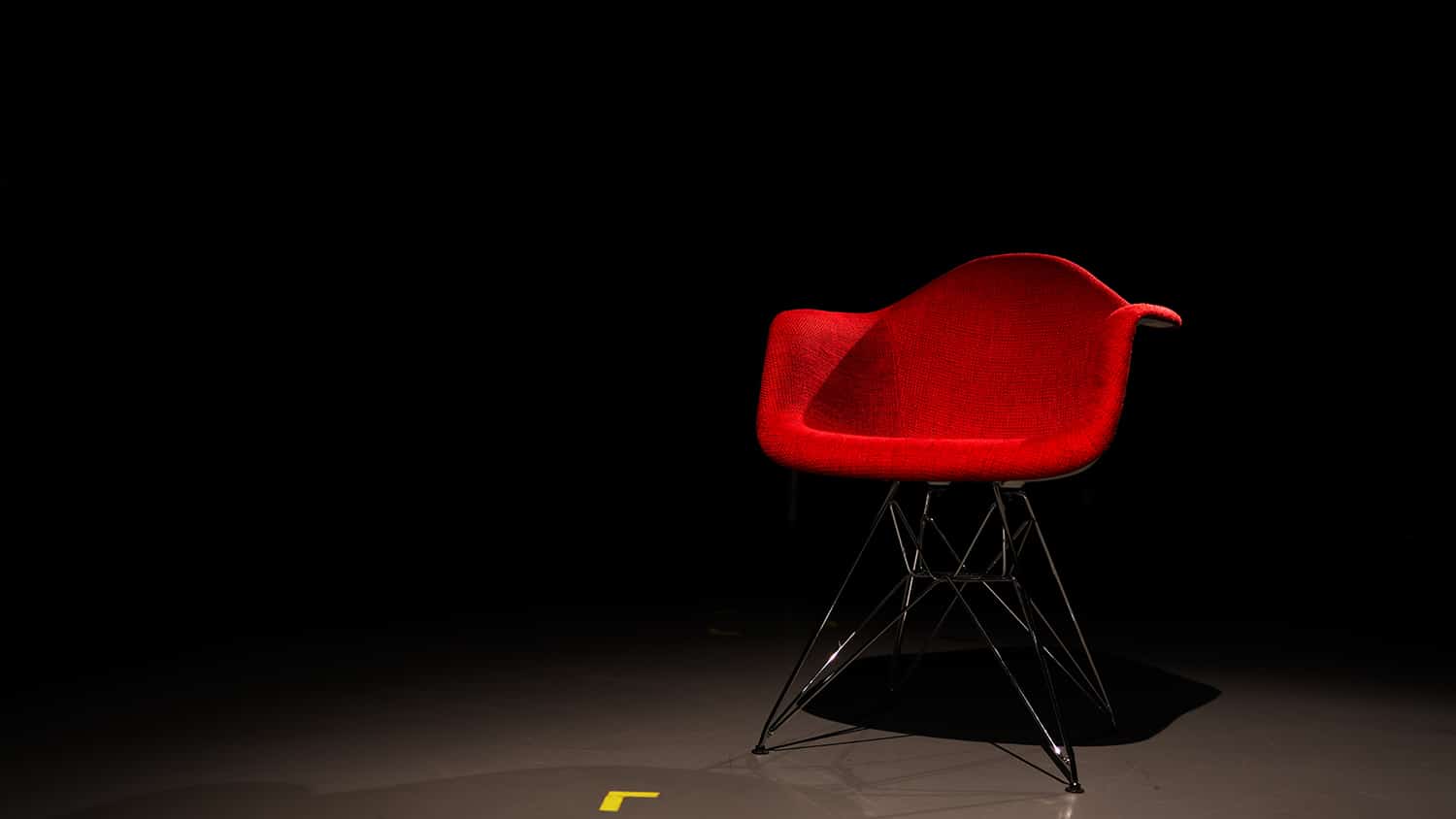 An empty red chair in a dark room.