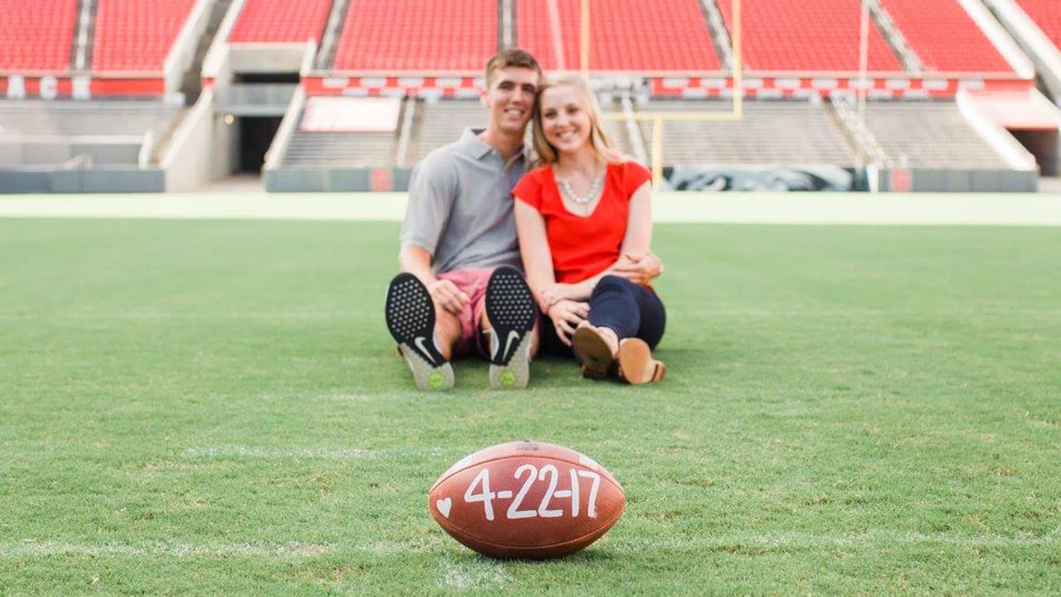 Alumni Wil Baumann and Olivia Clapp Baumann on the field of Carter-Finley Stadium on the day of their engagement.